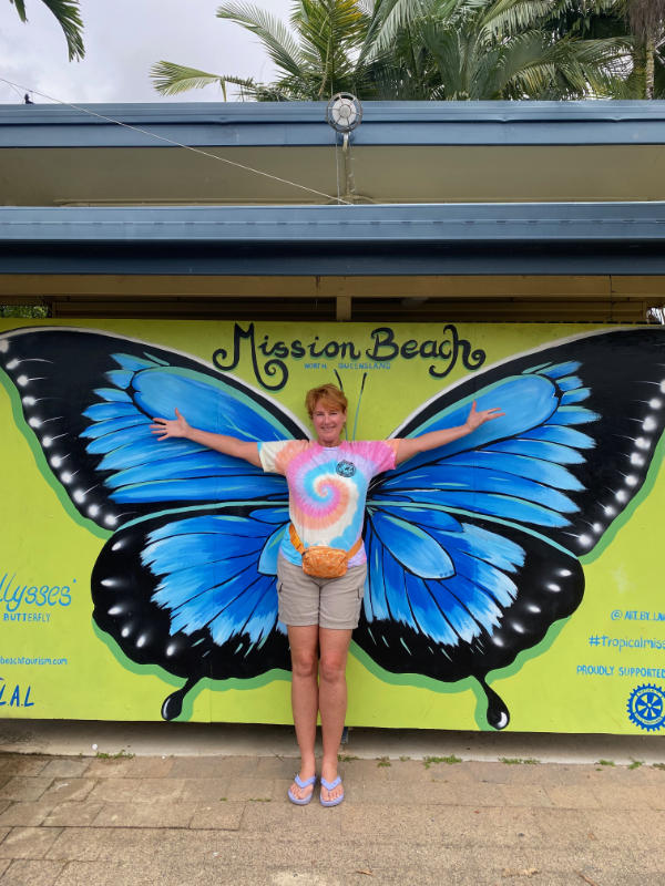 Pat standing against a butterfly painting at Mission Beach.